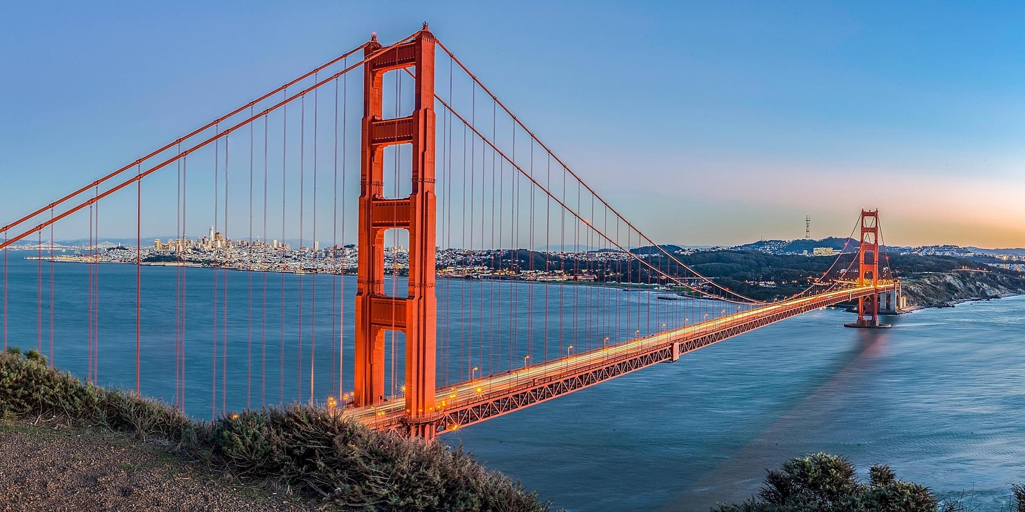 The Golden Gate Bridge at dusk with the San Francisco skyline across the bay