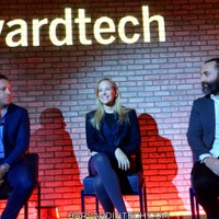 Three panelists seated on stage in front of an illuminated harvardtech sign