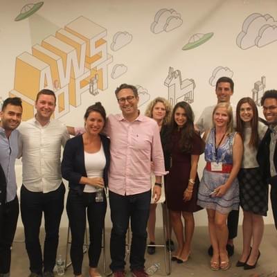 A group of attendees posing together in front of an AWS Loft mural