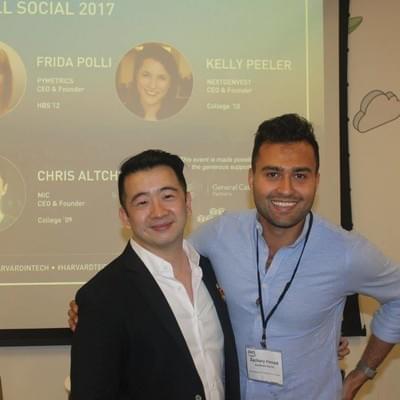 Two attendees posing in front of a slide introducing the event's founder speakers