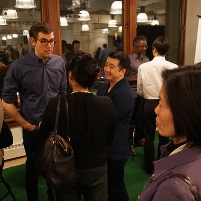 Attendees standing and talking in small groups at an evening reception