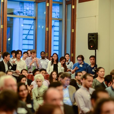 A crowded reception hall with attendees standing and seated in conversation