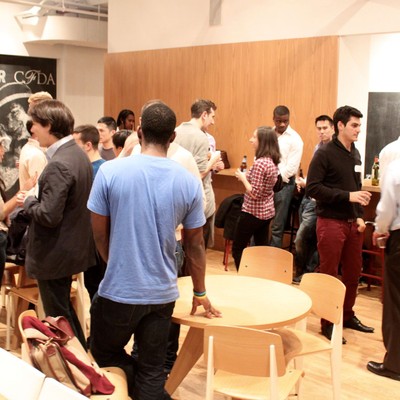 Attendees standing and talking around high tables at a casual evening mixer