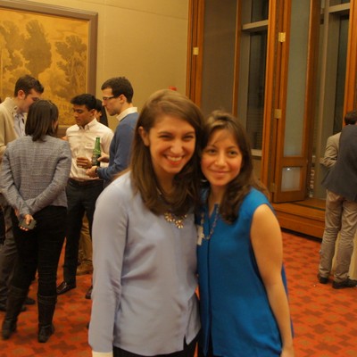 Two attendees smiling for the camera at a reception in a wood-panelled room