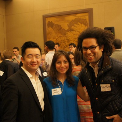 Three attendees wearing name badges posing together at a reception