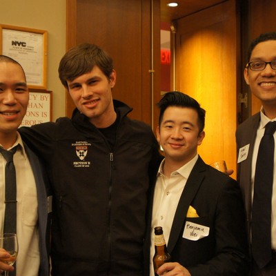 Four attendees in suits posing together at an evening event