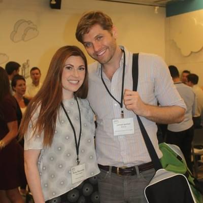 Two attendees wearing name badges smiling together at a reception